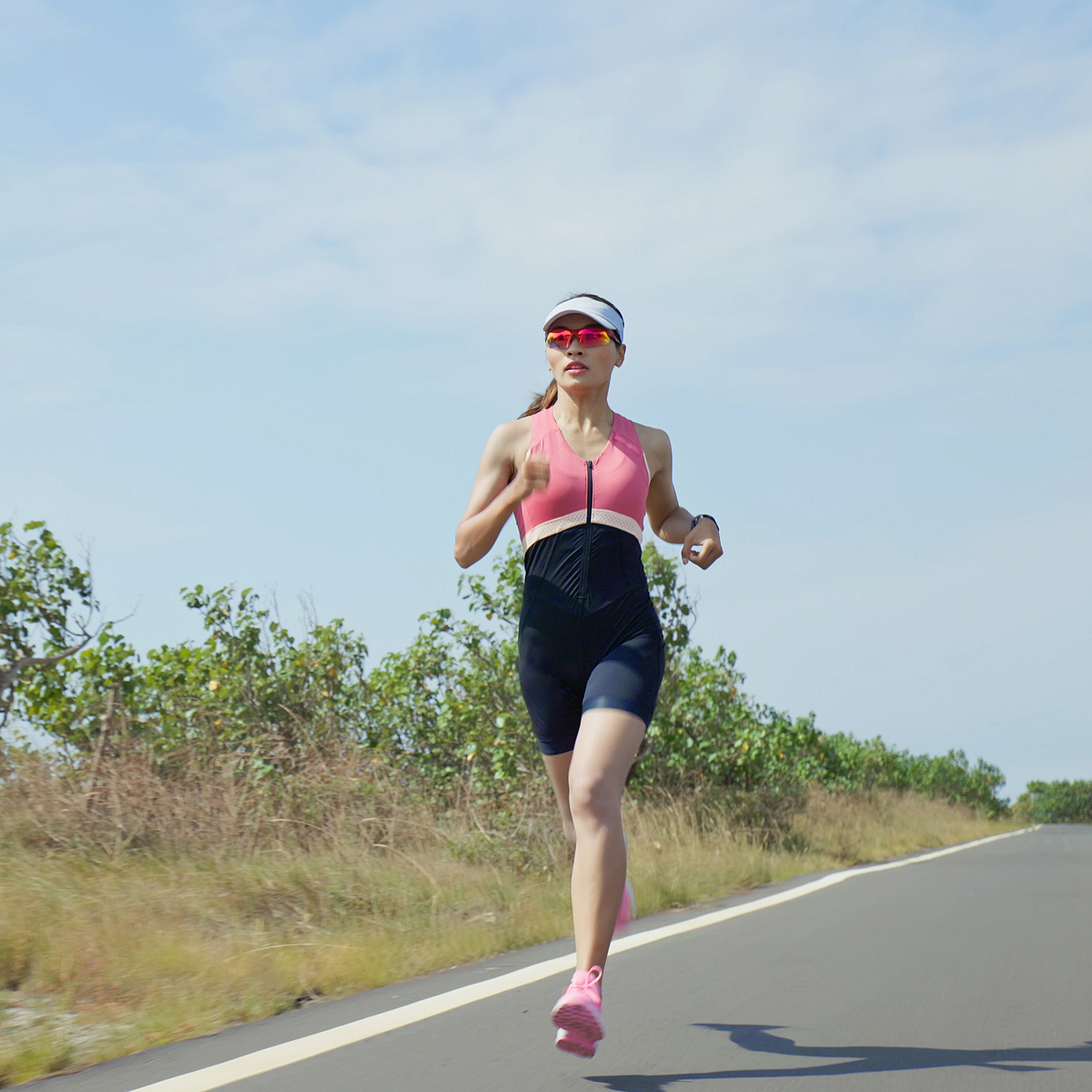 Triathlete running on a coastal road in race gear
